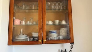 Ein Holzkabinett mit Glastüren, das verschiedene Geschirrteile und Gläser beherbergt.