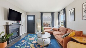 Un salon équipé d’un téléviseur  à écran plat, d’une cheminée, d’un canapé et d’une table basse.