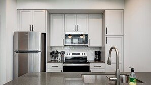 A modern kitchen with white cabinets, stainless steel appliances, and a granite countertop. - 1 King Bed/1Bth - Broad Ripple (Indianapolis)
