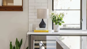 A kitchen area with a window, a potted plant, a lamp, and a stack of cookbooks. - Le Reve (Atlanta)