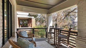 A covered balcony with wicker furniture, a view of the surrounding area, and a brick wall. - Le Reve (Atlanta)