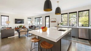 A modern kitchen with a large island, bar stools, and pendant lighting. - Le Reve (Atlanta)