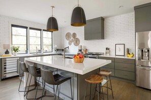 A modern kitchen with a central island, bar stools, and stainless steel appliances. - Le Reve (Atlanta)