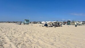 Una platja amb una torre de socorrisme, ombrel·les i cadiretes de platja.