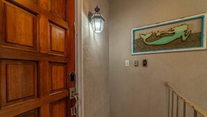 Una porta de fusta amb una làmpada moderna i una obra d'art emmarcada a la paret.