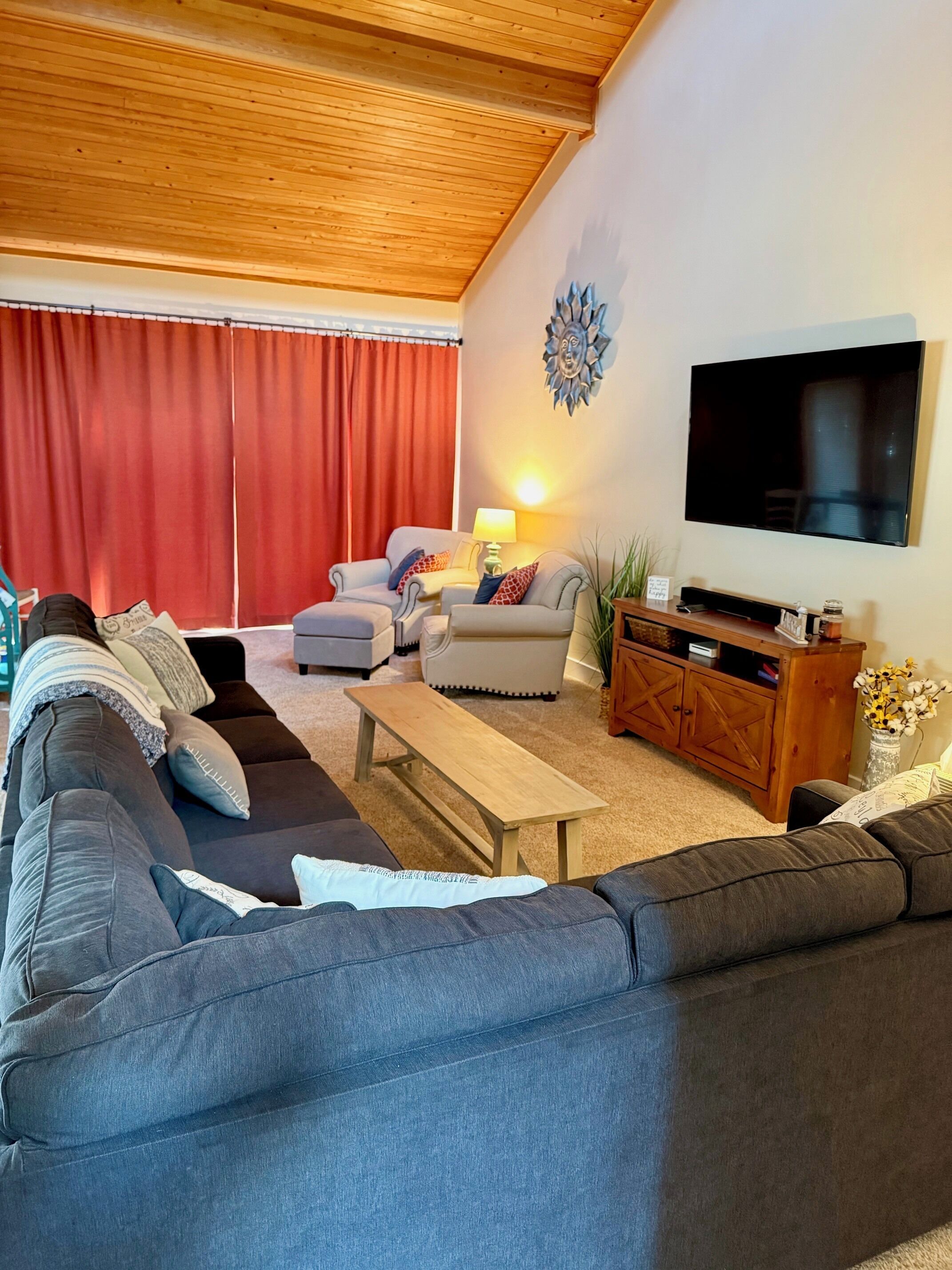 Una sala de estar con un sofá, una mesa de centro, un televisor y una cortina roja.