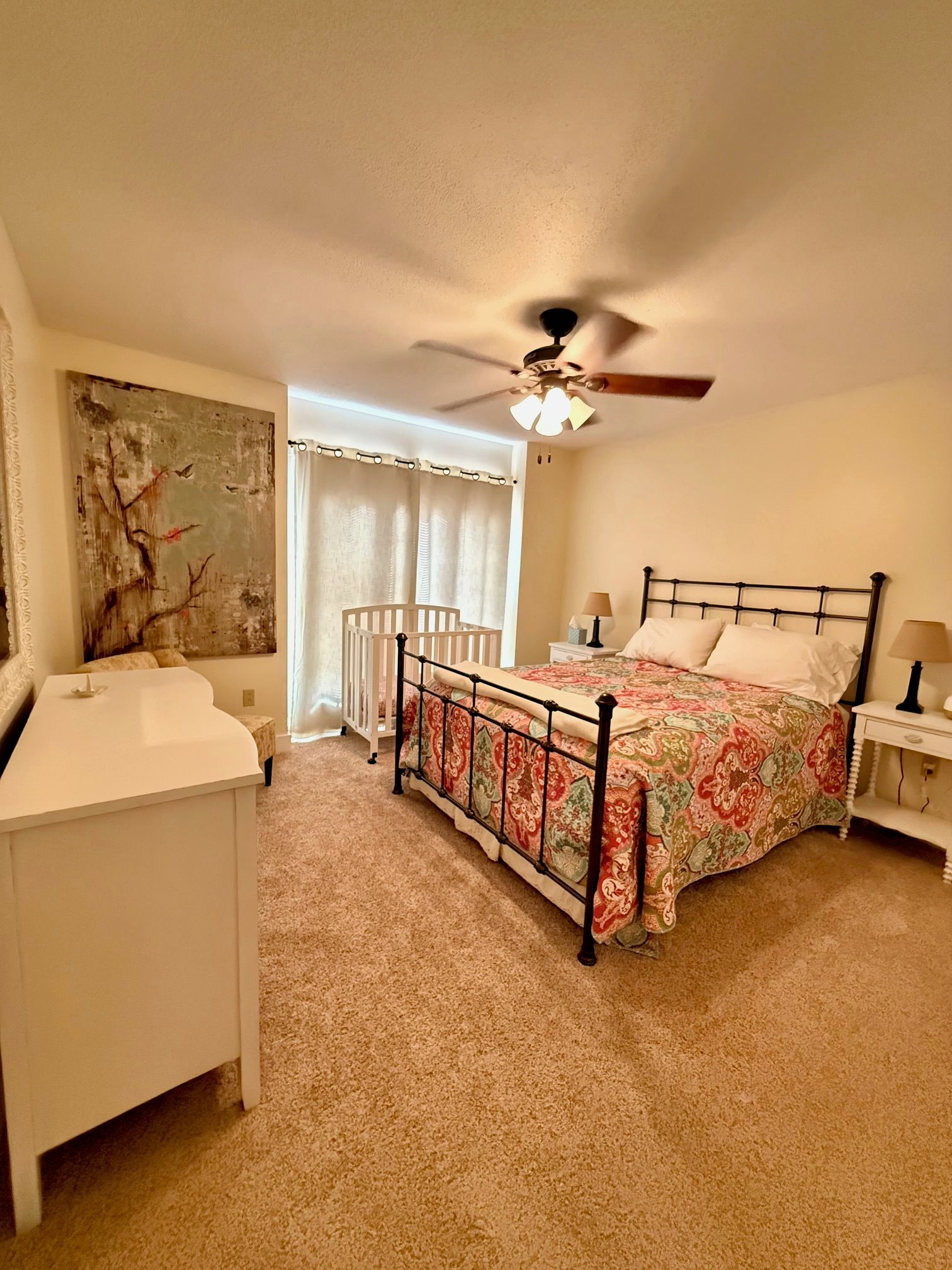 Un dormitorio con cama, escritorio, silla, ventilador de techo y radiador.