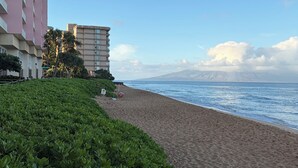 A beach with a building in the background. - Hilton Vacation Club Kaanapali Beach Club (Lahaina)