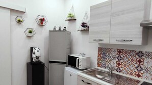 A compact kitchen with a refrigerator, microwave, and sink. There are hexagonal wall decorations and a patterned backsplash. - Angy's Little House is a small abode a 10-minute walk from downtown (Palermo)