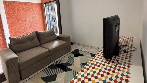 Un soggiorno con un divano, una televisione e un tappeto decorato.