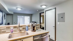 Une cuisine équipée d’un évier en acier inoxydable, d’une machine à café et d’un lave-vaisselle.