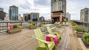 Une terrasse sur le toit, avec des espaces de repos en plein air, des plantes en pot et une vue sur les bâtiments de la ville.