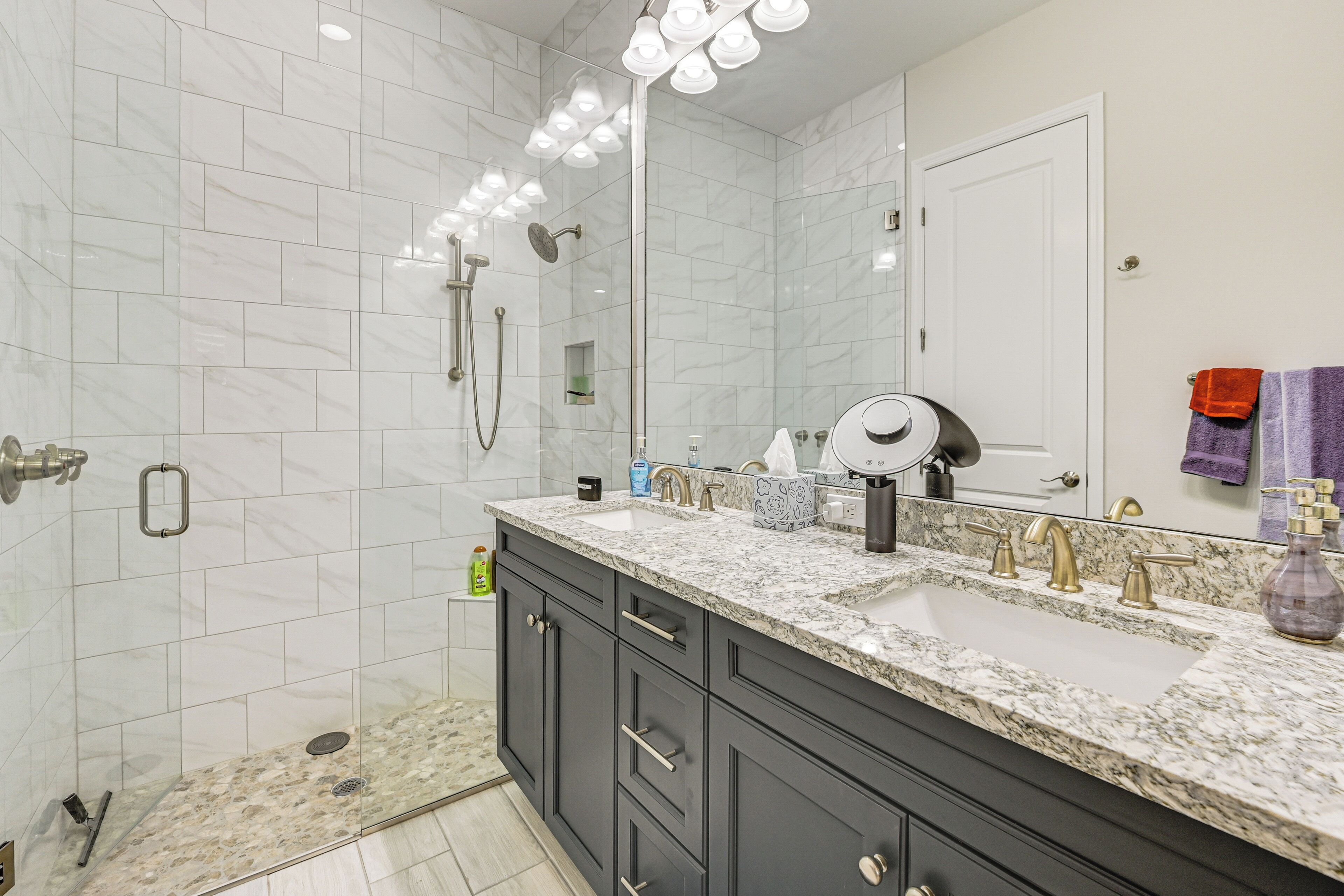 A modern bathroom with two sinks, dark cabinets, and a large mirror.