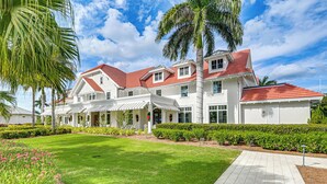 A large, white building with a red roof, surrounded by well-maintained lawns and palm trees. - 3 Mi to Naples Beach! Couple's Resort Getaway (Naples)