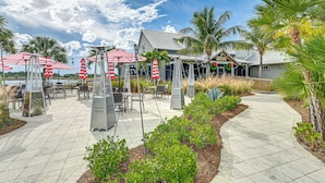 An outdoor patio area with tables and chairs, surrounded by palm trees and greenery. - 3 Mi to Naples Beach! Couple's Resort Getaway (Naples)