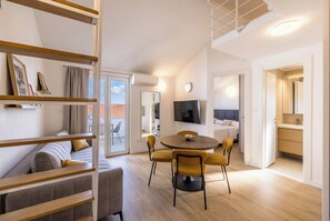 Ein modernes Wohnzimmer mit einer Couch, einem Esstisch mit Stühlen, einem Fernseher und einer Treppe.