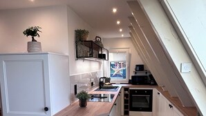 A modern kitchen with white cabinetry, a wooden countertop, and a built-in oven. - Chalet on the Biggesee (Olpe)