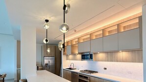 A modern kitchen with a long island, built-in appliances, and pendant lighting.