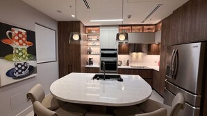 Uma cozinha moderna com ilha central, eletrodomésticos de aço inoxidável e iluminação pendente.