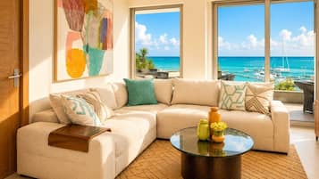 A modern living room with a sectional sofa, a glass coffee table, and a large window offering a view of the ocean and boats.
