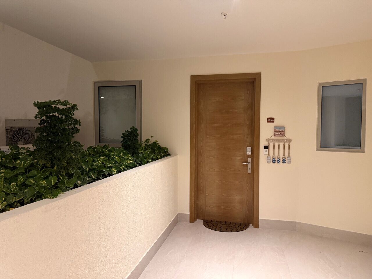 A hallway with a wooden door, a small window, and a wall-mounted sign.