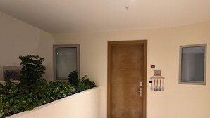 Um corredor com porta de madeira, uma janela pequena e uma placa fixada na parede.
