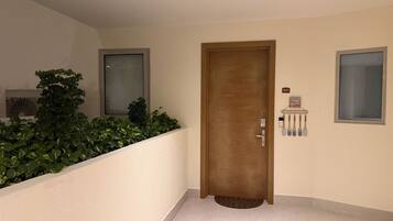 A hallway with a wooden door, a small window, and a wall-mounted sign.