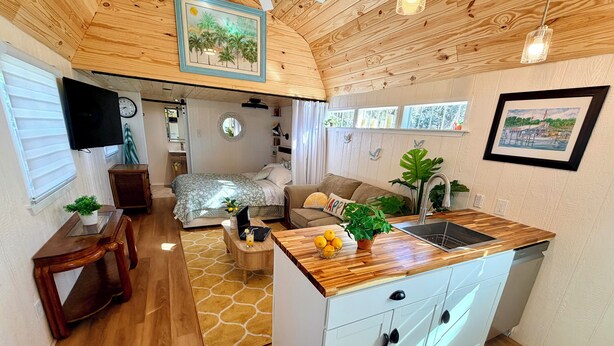 Una cocina compacta con encimeras de madera, un lavamanos y una zona de comedor con sofá y una mesa pequeña.