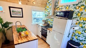 Una cocina compacta con encimera de madera, electrodomésticos blancos y ventana con vistas.