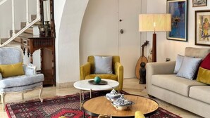 A living room with a staircase, a yellow armchair, a beige sofa, and a coffee table with shoes. - Maison Lella Kmar Sidi Bousaid (Site archéologique de Carthage)