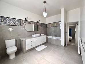 Une salle de bain moderne équipée de toilettes, d’un lavabo, d’un meuble-lavabo et d’une baignoire.
