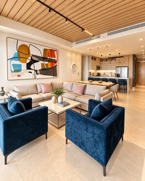 A modern living room with a sofa set, a coffee table, and a kitchen in the background.
