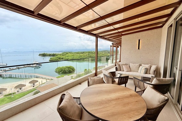 Penthouse balcony featuring an outdoor dining table, seating area, and direct ocean views.