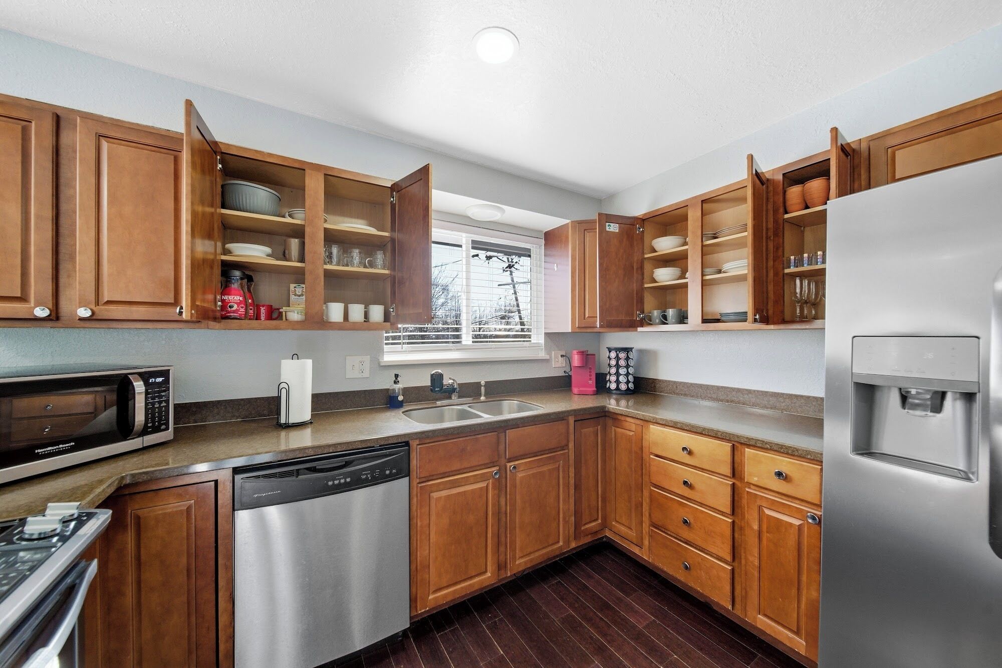 A modern kitchen with wooden cabinets, stainless steel appliances, and a window providing natural light.