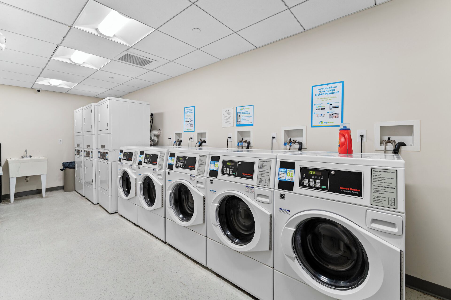 A laundry facility with multiple washing machines, a sink, and a fire extinguisher.