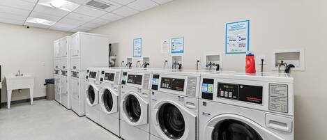 A laundry facility with multiple washing machines, a sink, and a fire extinguisher.
