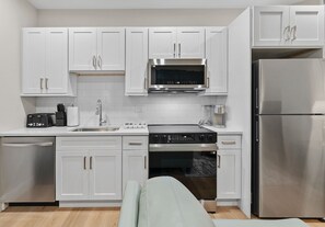 A modern kitchen with white cabinets, stainless steel appliances, and a built-in oven. - Luxury 2BR near Cambridge (Somerville)