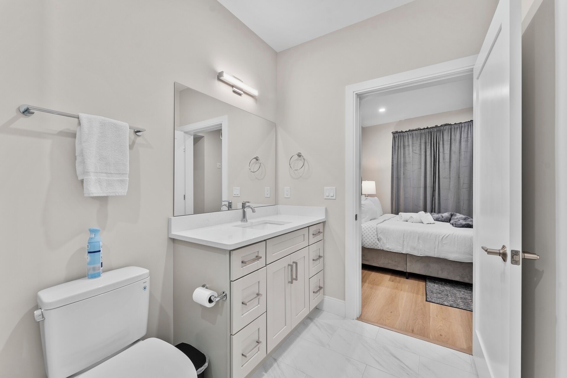 A modern bathroom with a toilet, sink, and mirror.