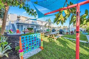 A patio area with a children's play area, including a tire hop game, picnic tables, and outdoor seating.