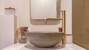 A bathroom with a large, round, beige sink, a gold faucet, and a mirror above it. - Terrific 4-bedroom house with AC in the Hamptons (East Hampton)