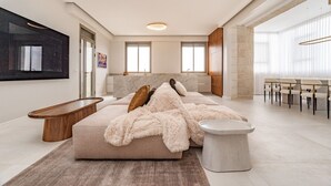 A modern living room with a large sofa, a coffee table, and a dining area with chairs. - Terrific 4-bedroom house with AC in the Hamptons (East Hampton)