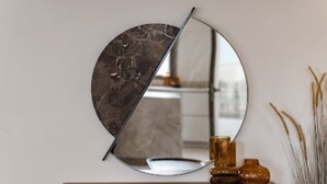 A round mirror with a marble-like surface, mounted on a wall above a wooden dresser with a white countertop. - Terrific 4-bedroom house with AC in the Hamptons (East Hampton)