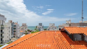 Un quartier résidentiel situé sur la côte, caractérisé par des toits recouverts de tuiles en terre cuite, des bâtiments modernes et une vue dégagée sur la mer.