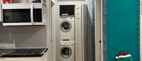 A compact kitchen with a microwave, oven, and a washing machine.