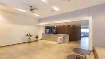 A spacious lobby with a reception desk, seating area, and a ceiling fan.