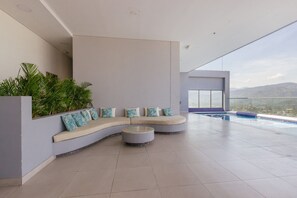 A modern interior with a curved sofa, a round coffee table, and a pool area. - U-GO Edificio Ambar Roca en Rodadero Sur (Santa Marta)