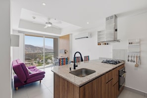 A modern kitchen with a central island, a built-in oven, and a gas stove. - U-GO Edificio Ambar Roca en Rodadero Sur (Santa Marta)