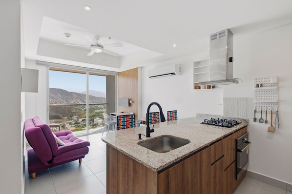 A modern kitchen with a central island, a built-in oven, and a gas stove. - U-GO Edificio Ambar Roca en Rodadero Sur (Santa Marta)