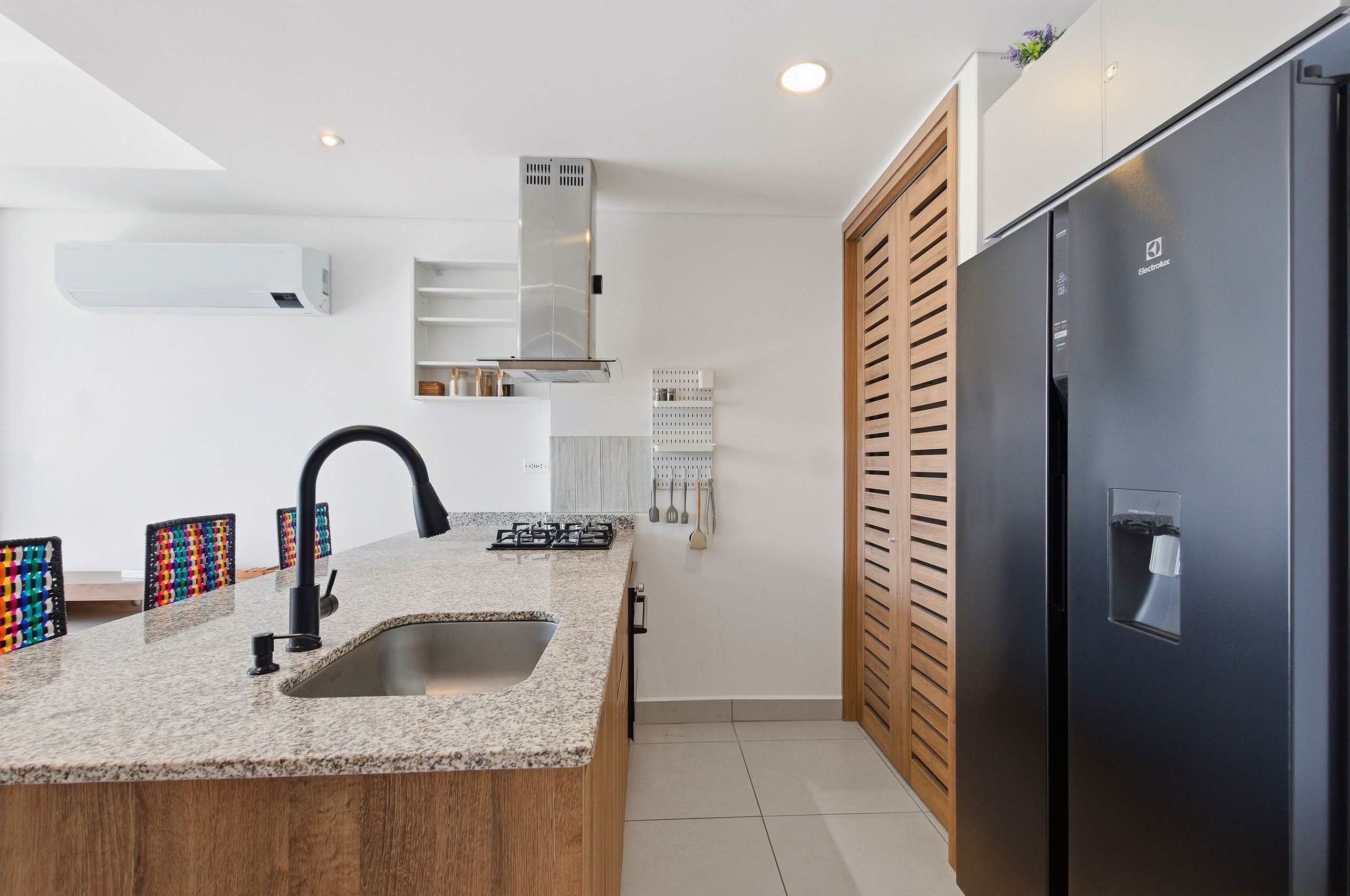 A modern kitchen with a granite countertop, stainless steel appliances, and a built-in sink.