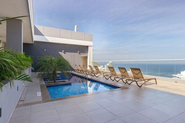 A rooftop pool with lounge chairs and a view of the ocean. - U-GO Edificio Ambar Roca en Rodadero Sur (Santa Marta)